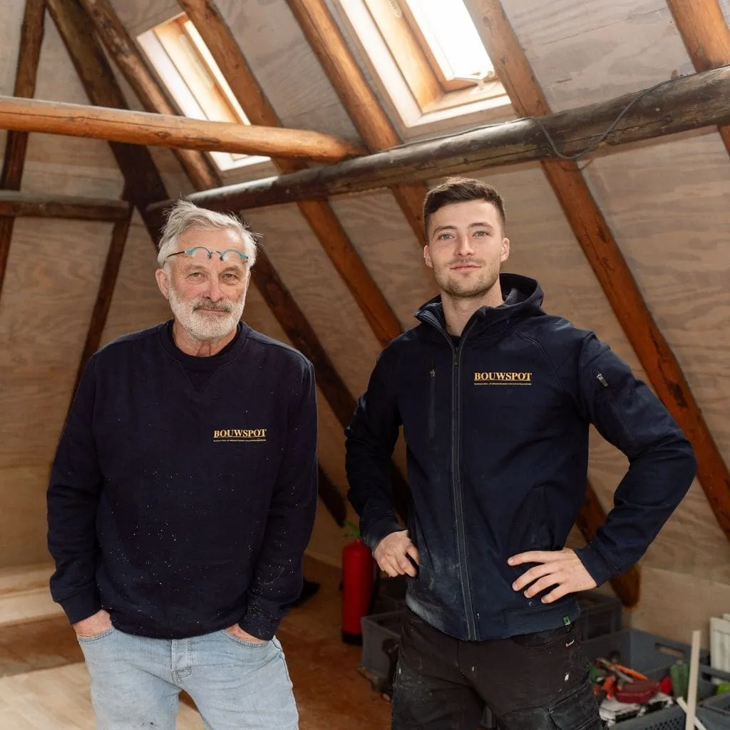 Merik Sliedrecht en zijn vader Rens in Bouwspot-werkkleding op een zolder met houten kapconstructie
