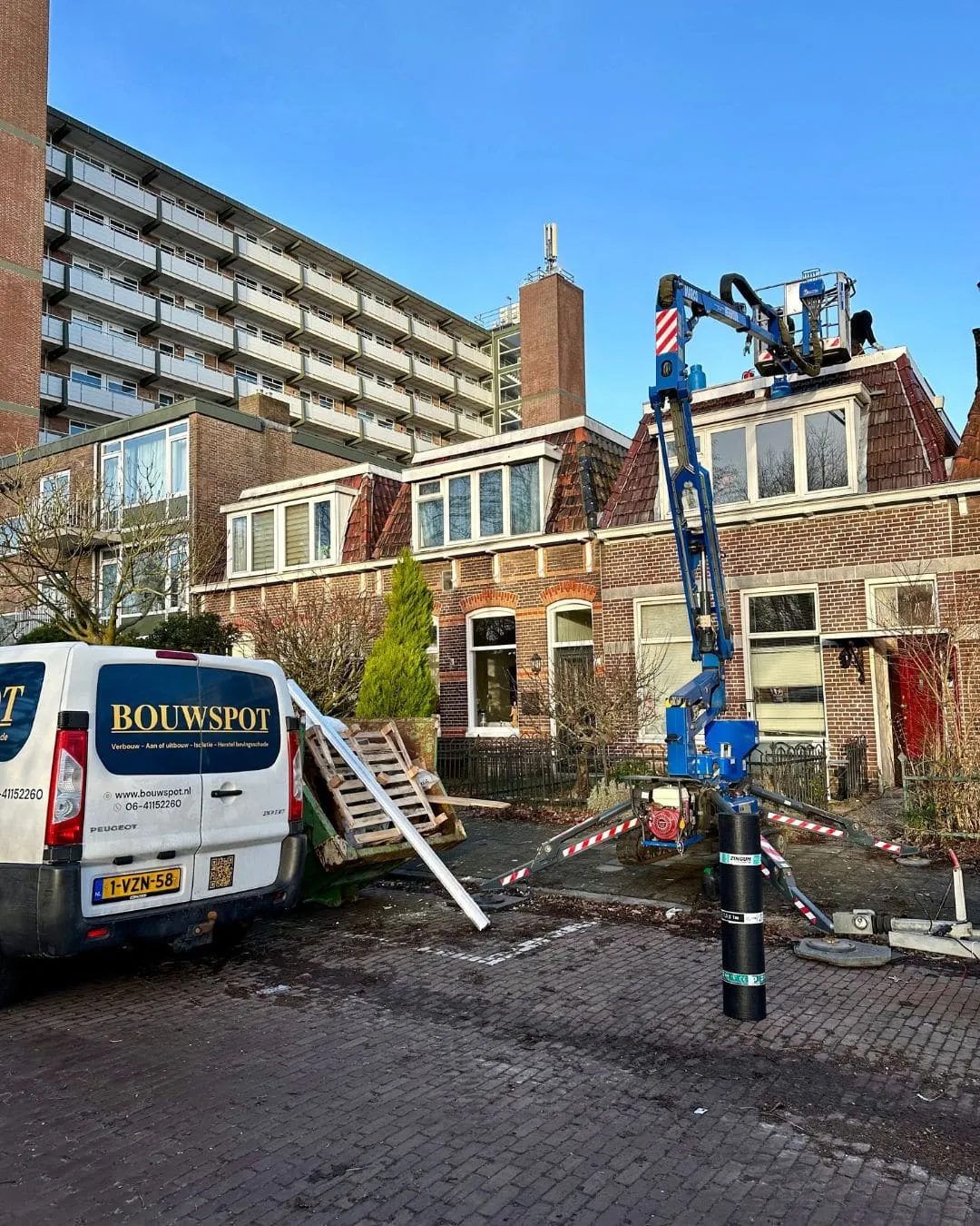 Bouwspot-bus en hoogwerker voor een woning tijdens de renovatie