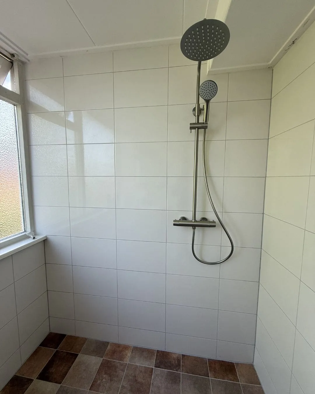 Nieuw betegelde badkamer met regendouche en thermostaatkraan in een gerenoveerde woning in Groningen