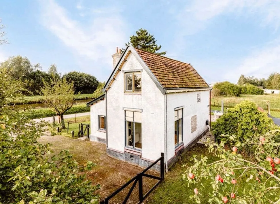Wit gepleisterd vrijstaand huis met pannendak in een landelijke omgeving
